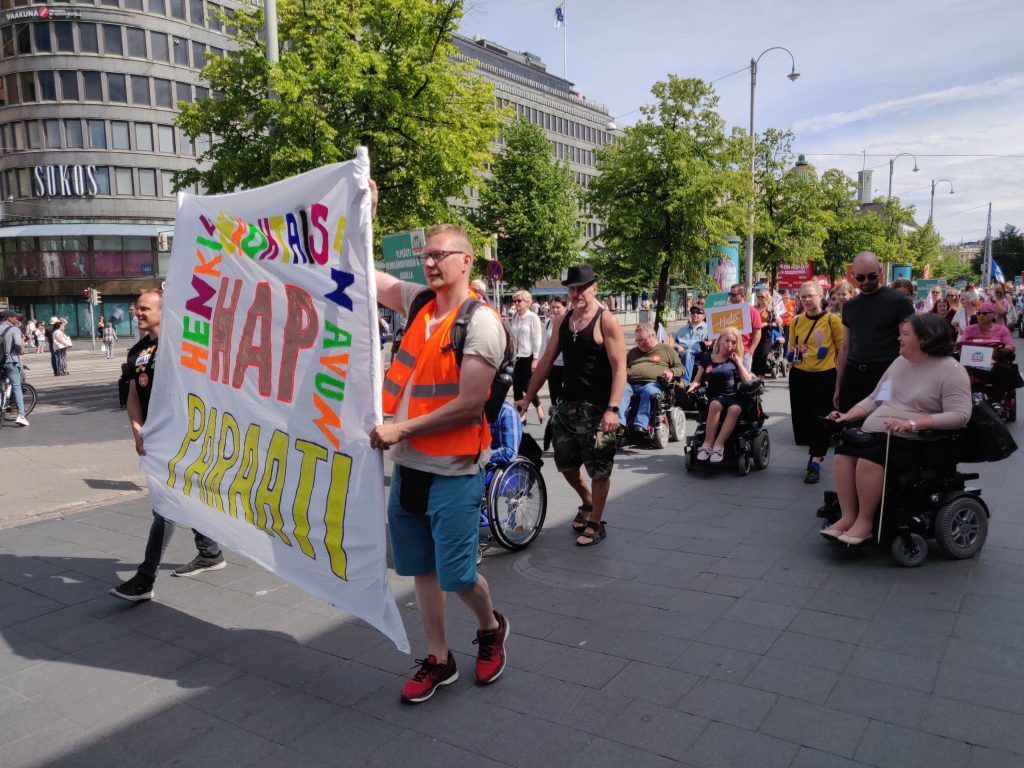 Henkilökohtaisen avun paraati. Ihmisiä kulkemassa joukkona Mannerheimintiellä Helsingissä.