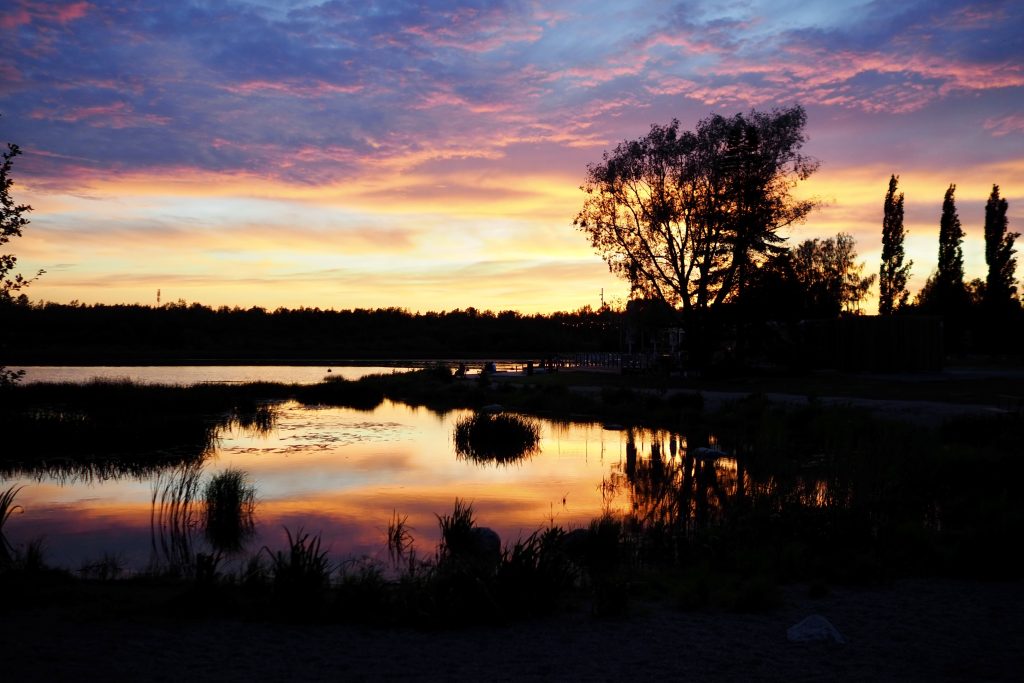 Auringonlasku, joka heijastuu järveen.