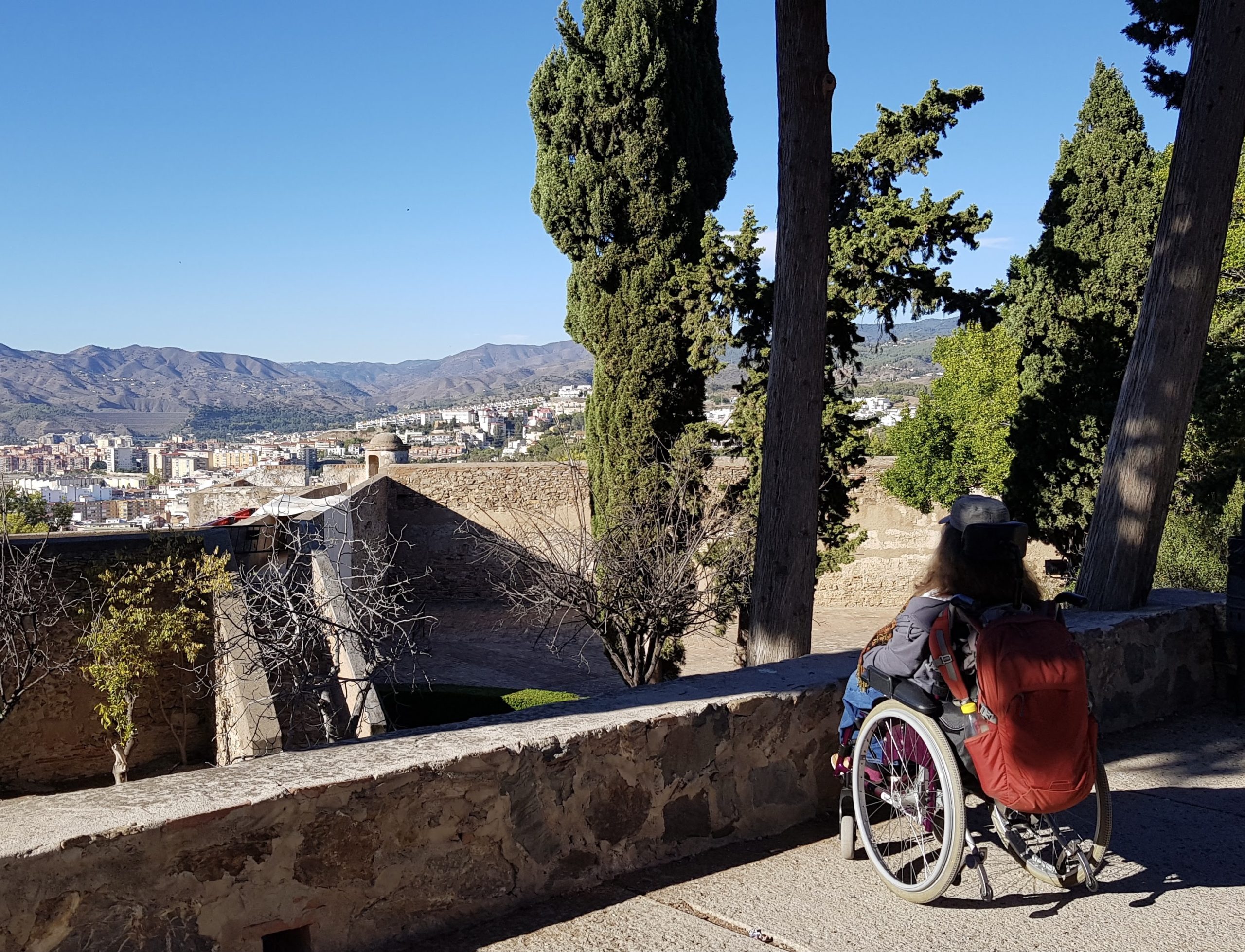 Venla Räty  istuu pyörätuolissa kauniin maiseman äärellä Malagassa.