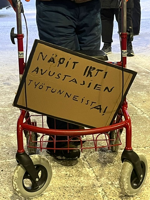 Mielenosoituskyltti: Näpit irti avustajien työtunneista. 