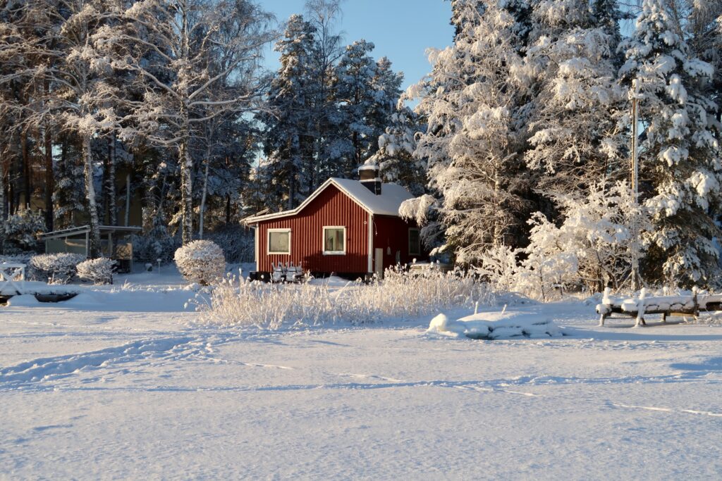 Talvinen maisema, jossa paljon lunta ja punainen puutalo.