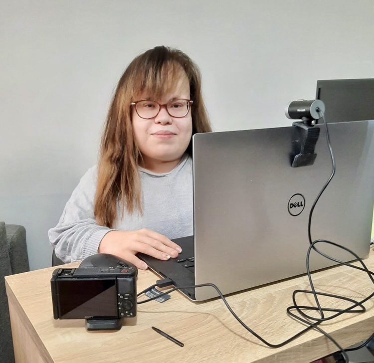Nainen istuu kannettavan tietokoneen äärellä.